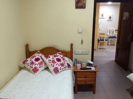 Un dormitorio con una cama, mesita de noche y sillas.
