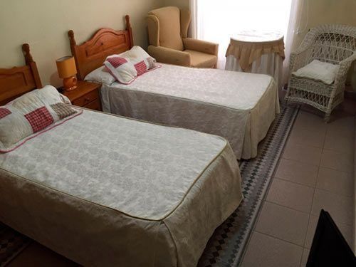 Un dormitorio con dos camas, una silla y una mesa.