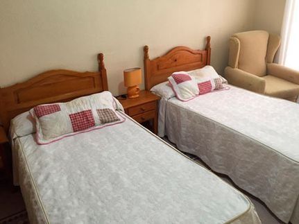 Un dormitorio con dos camas, una silla y una lámpara.