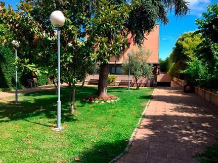 Una casa grande está rodeada de árboles y un exuberante césped verde.