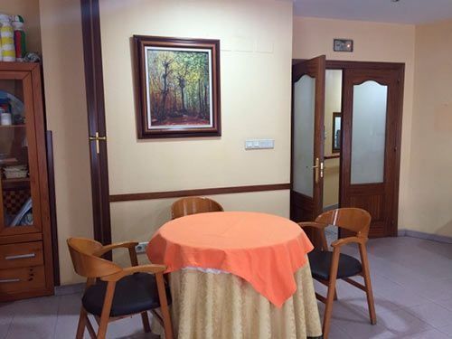 Una habitación con una mesa y sillas y un cuadro en la pared.