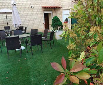 Un patio con mesas, sillas y sombrillas frente a un edificio de ladrillo.