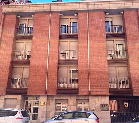 Dos coches están aparcados delante de un gran edificio de ladrillo.
