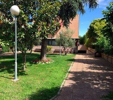 Una pasarela de ladrillos que conduce a un edificio con árboles y césped.
