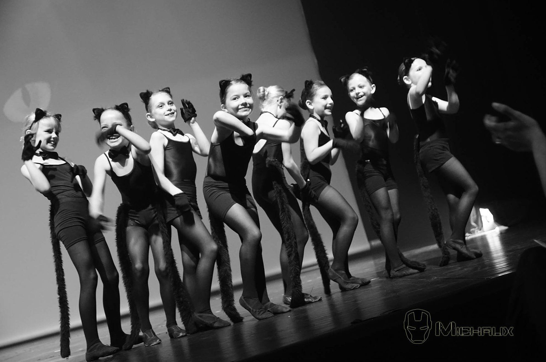 Groupe d'enfants sur scène, déguisés en chats, exécutant une chorégraphie.
