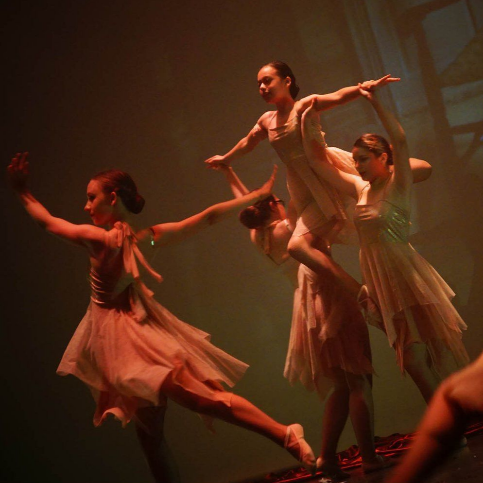 Des danseurs de ballet en robes pêche effectuent un porté sur scène.