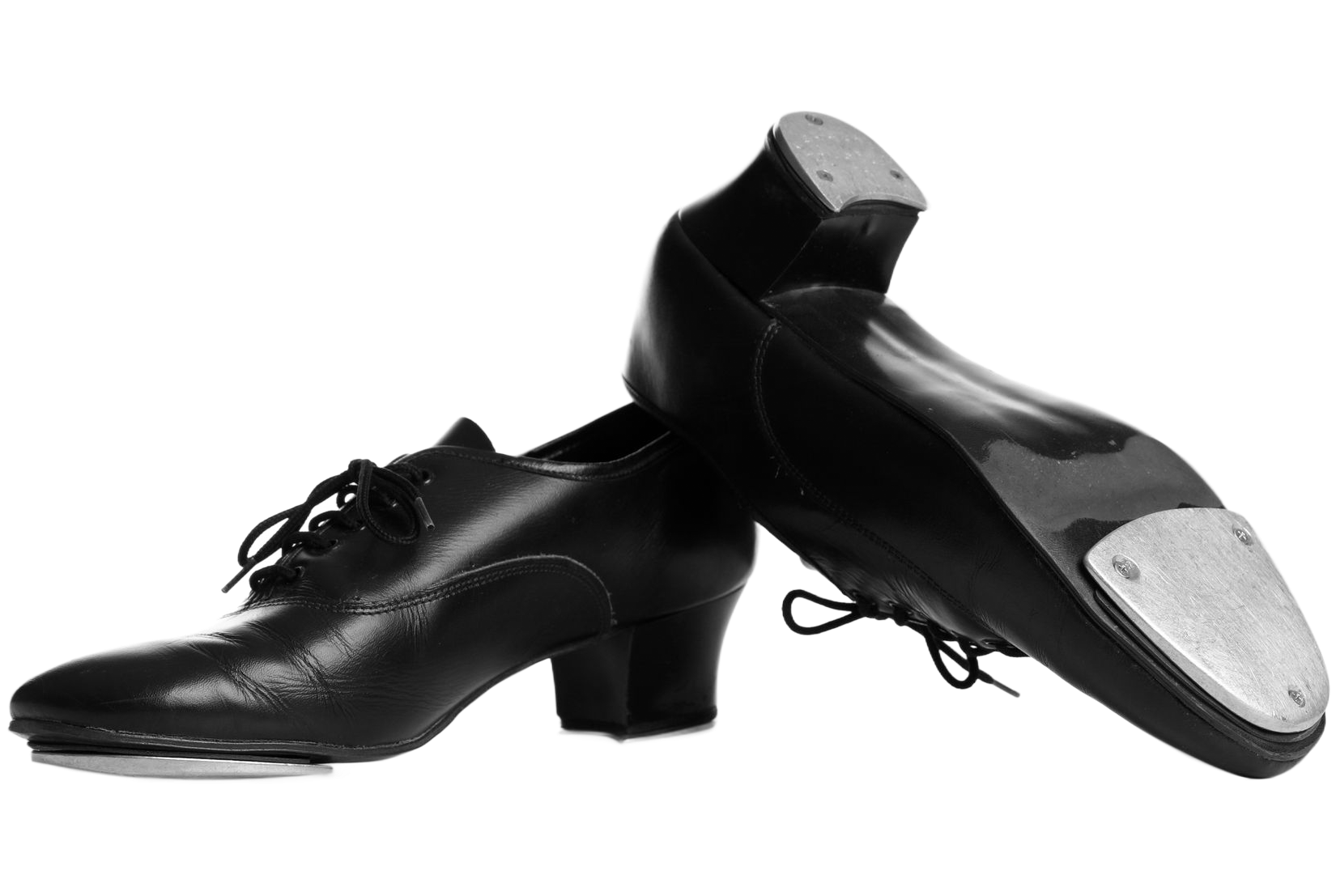 Chaussures de claquettes noires avec claquettes en métal, inclinées sur une surface blanche.