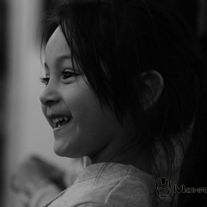 Enfant souriant, en noir et blanc, regardant sur le côté.