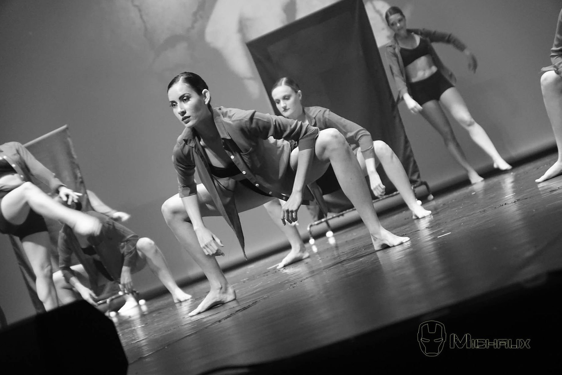 Danseurs sur scène, en noir et blanc. Ils exécutent une chorégraphie moderne, accroupis et en mouvement.