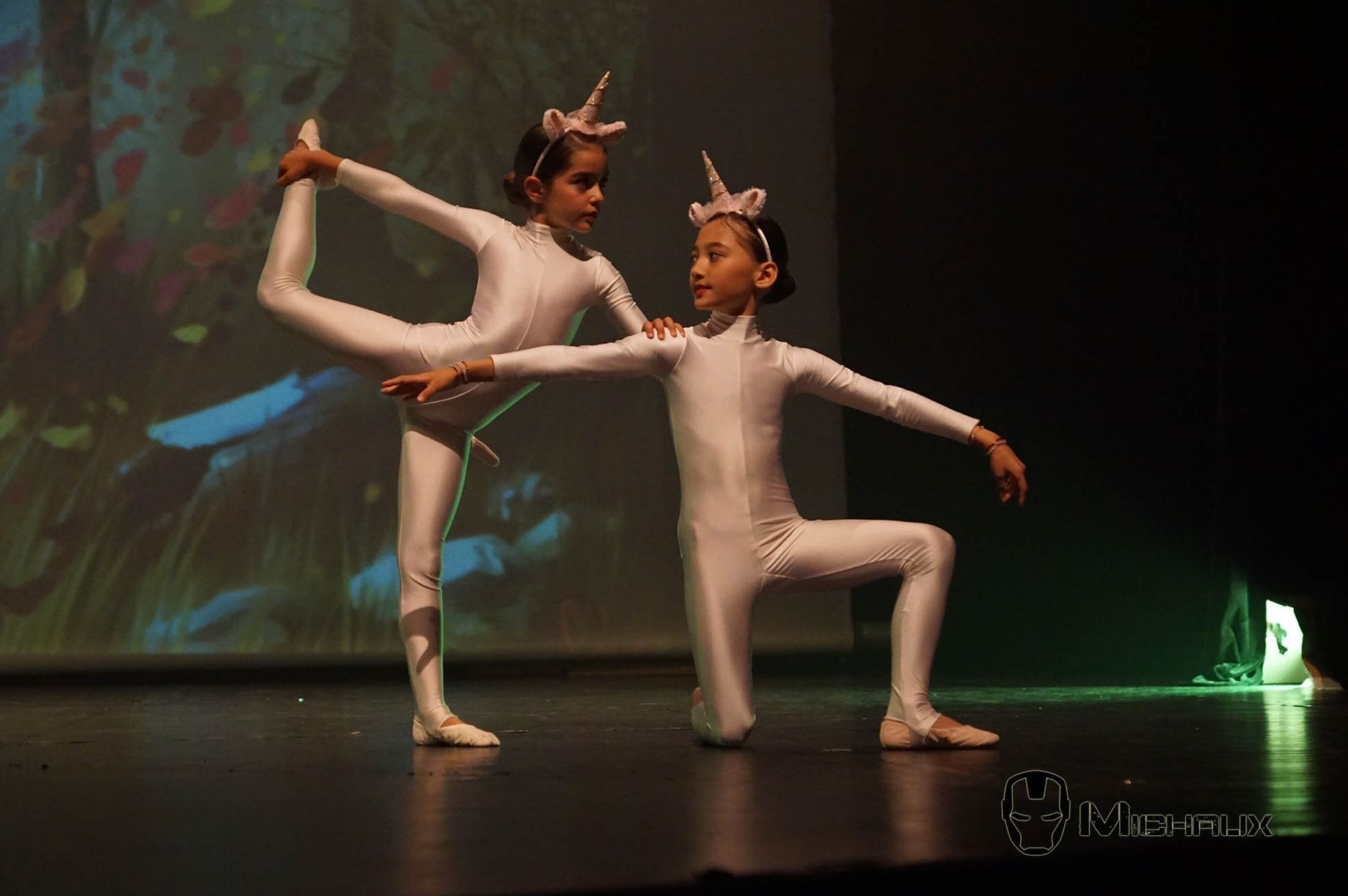 Deux jeunes danseurs en costumes de licorne se produisent sur scène.