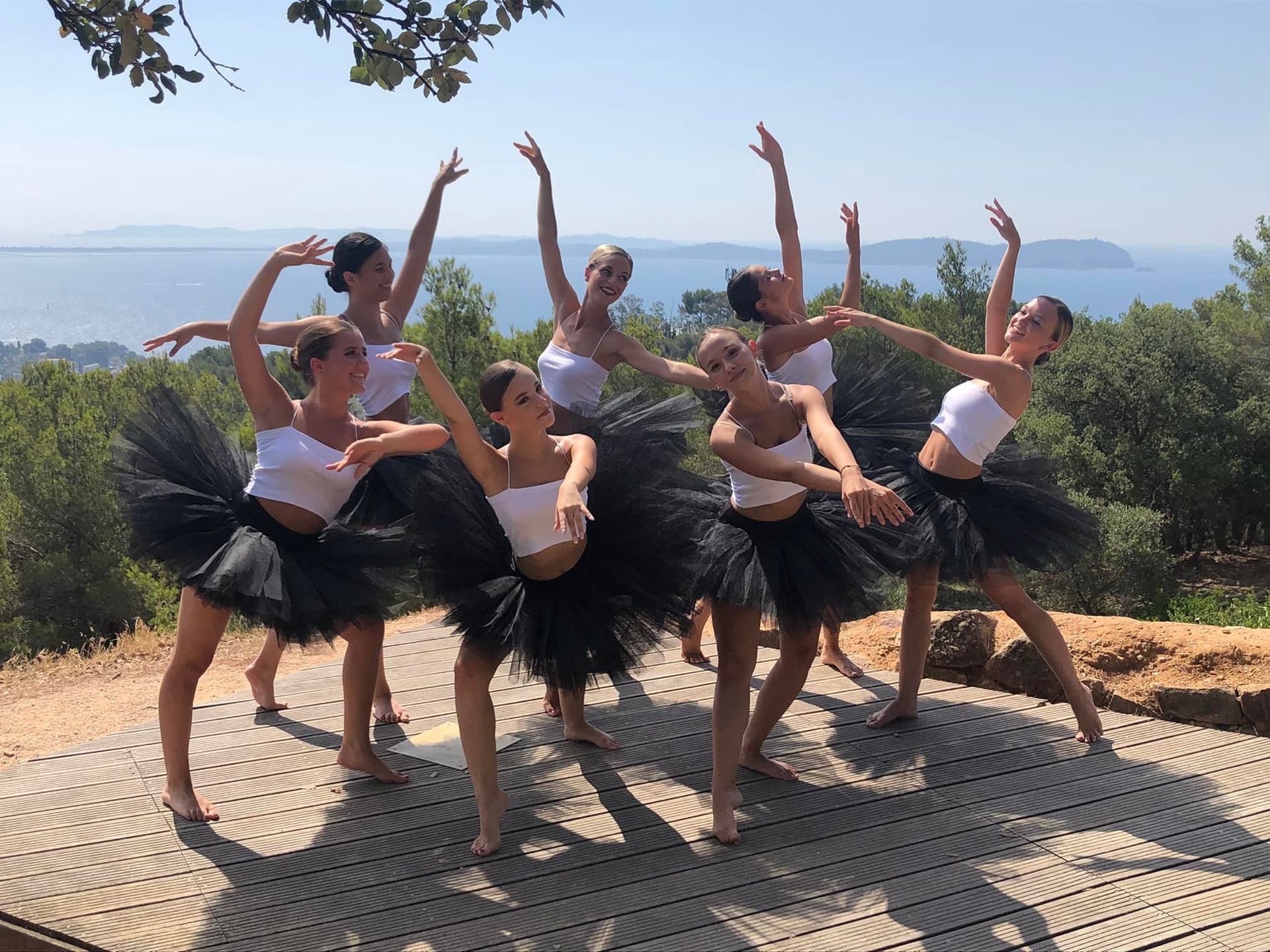 Des danseurs en robes rouges exécutent un porté sur scène, l'un d'eux est cambré avec les jambes écartées.