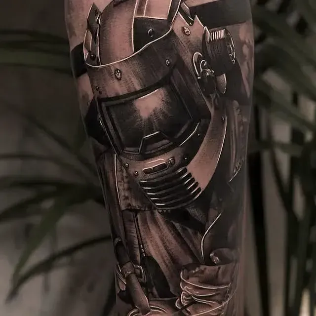 Tatuaje en negro y gris de un casco y traje de soldador en un brazo, detalle en sombreado.