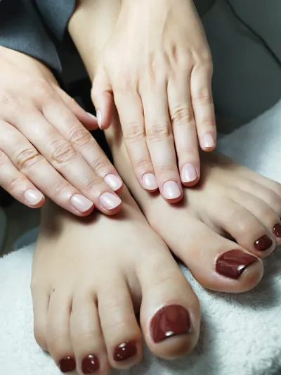 Un primer plano de las manos y los pies de una mujer con esmalte de uñas rojo.