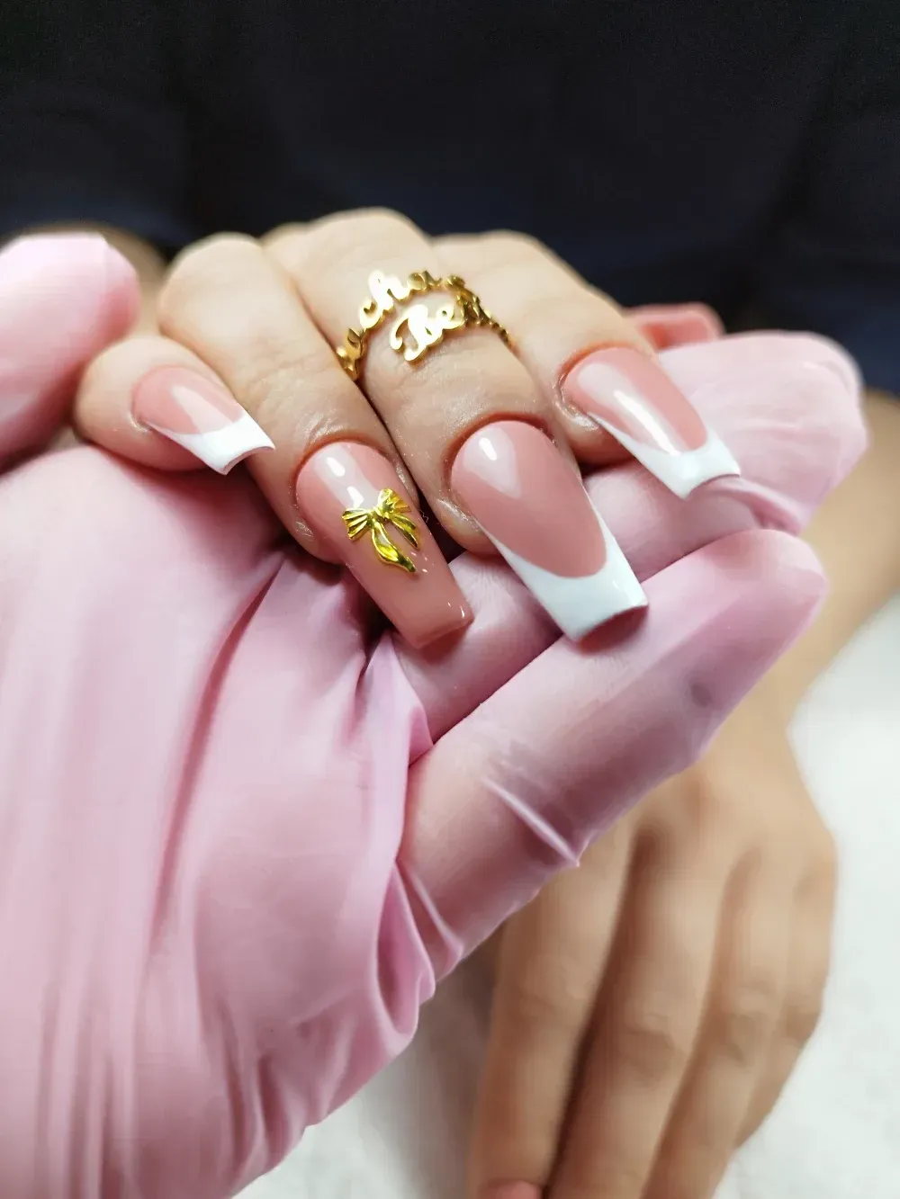 Una mujer que lleva guantes rosas se sujeta las uñas.