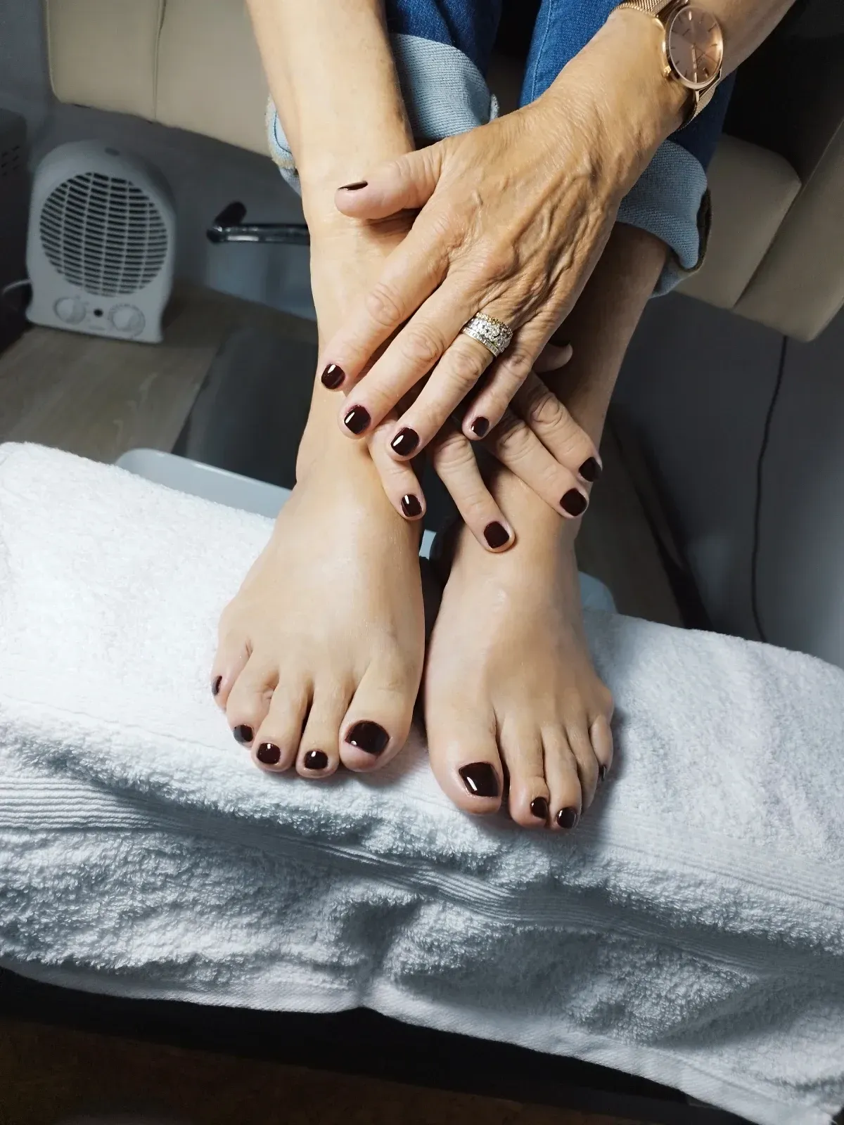 Los pies de una mujer están sentados sobre una toalla blanca con sus manos sobre ellos.