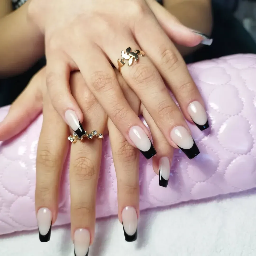 Un primer plano de las uñas de una mujer con un anillo en el dedo.