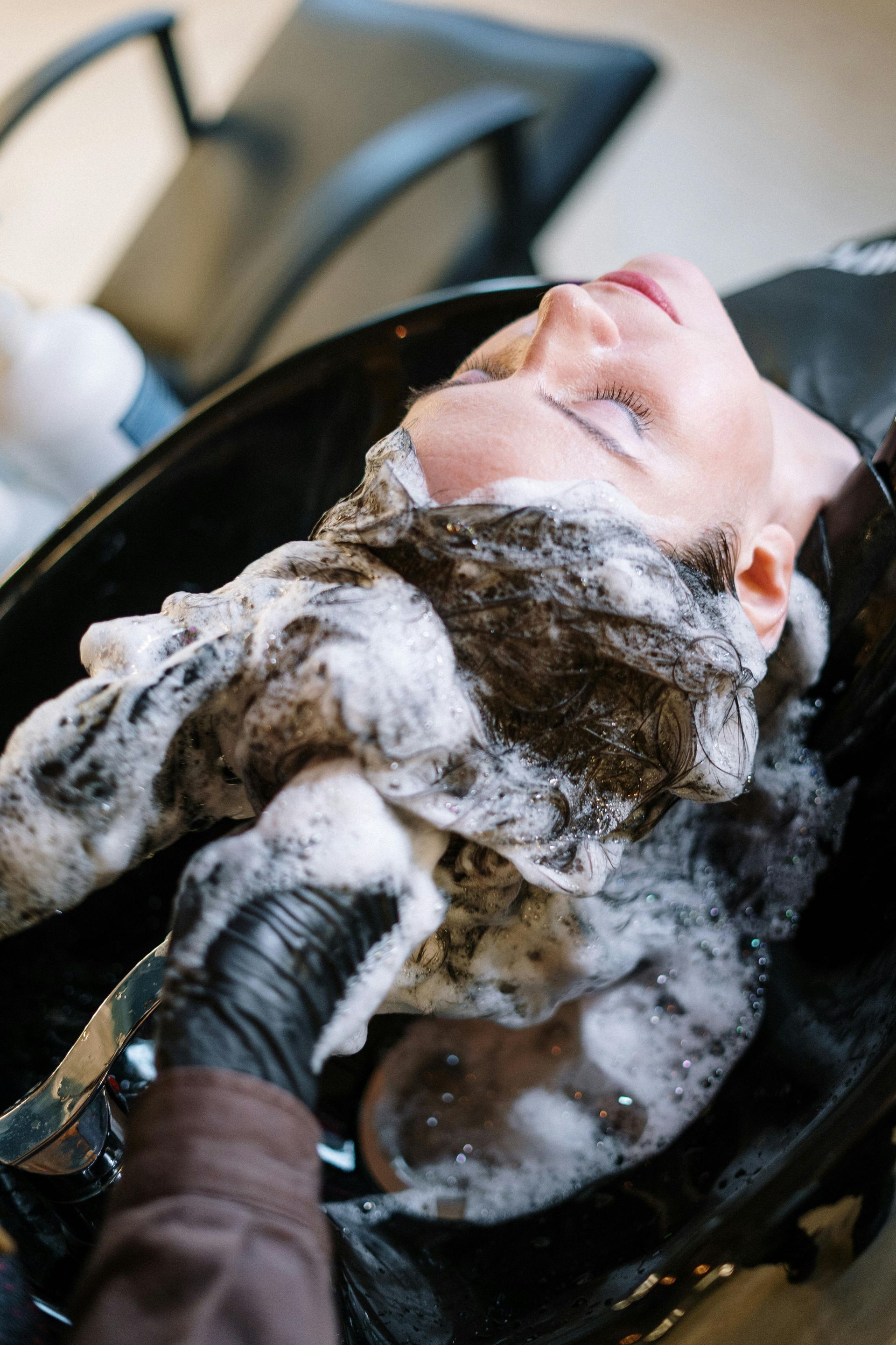 Una mujer se lava el cabello en un lavabo de una peluquería.