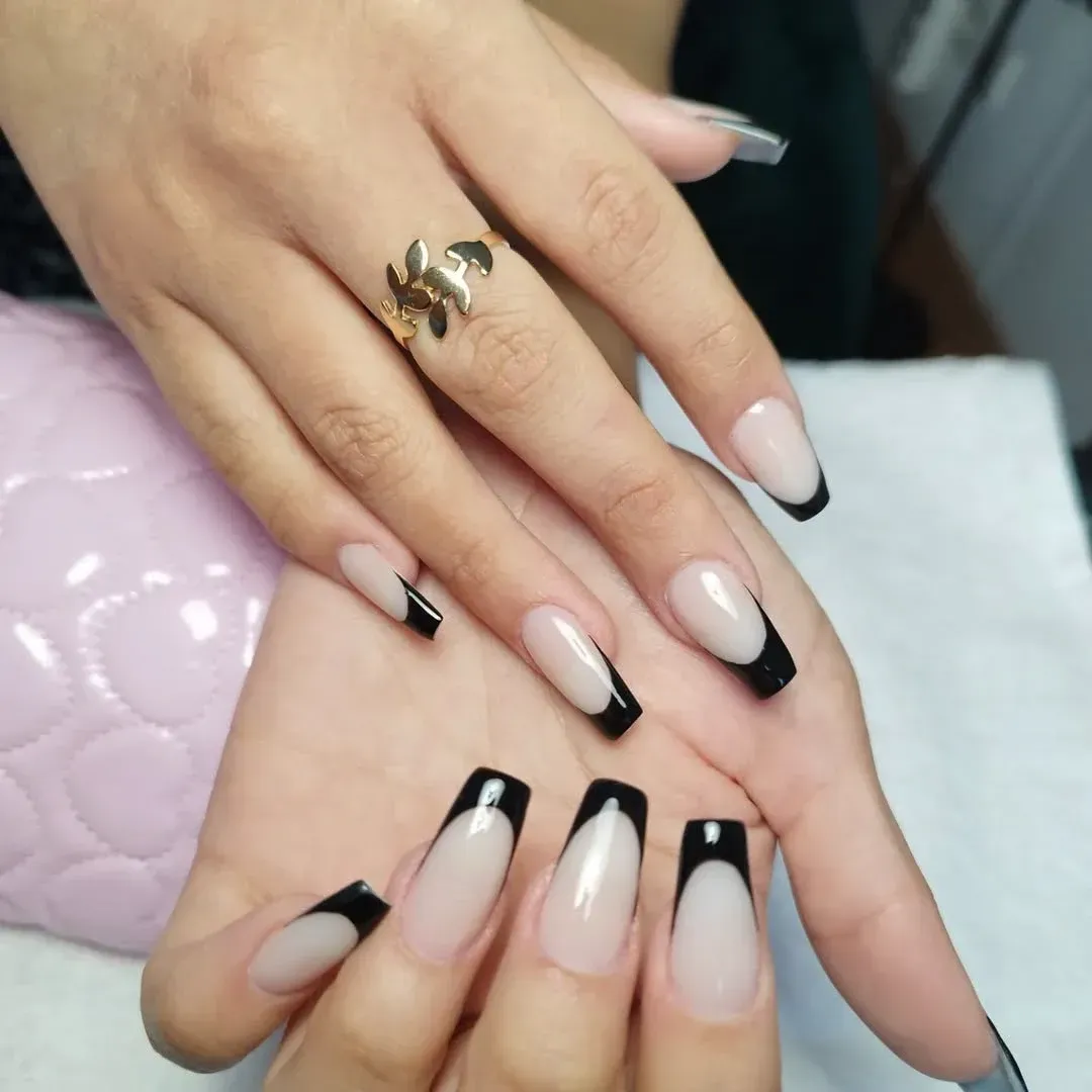 La mano de una mujer con uñas largas y un anillo en el dedo.