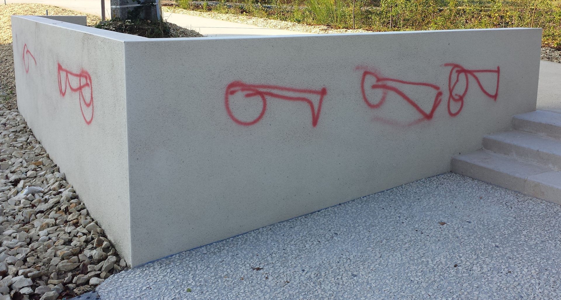 Muret en béton avec graffitis rouges peints à la bombe