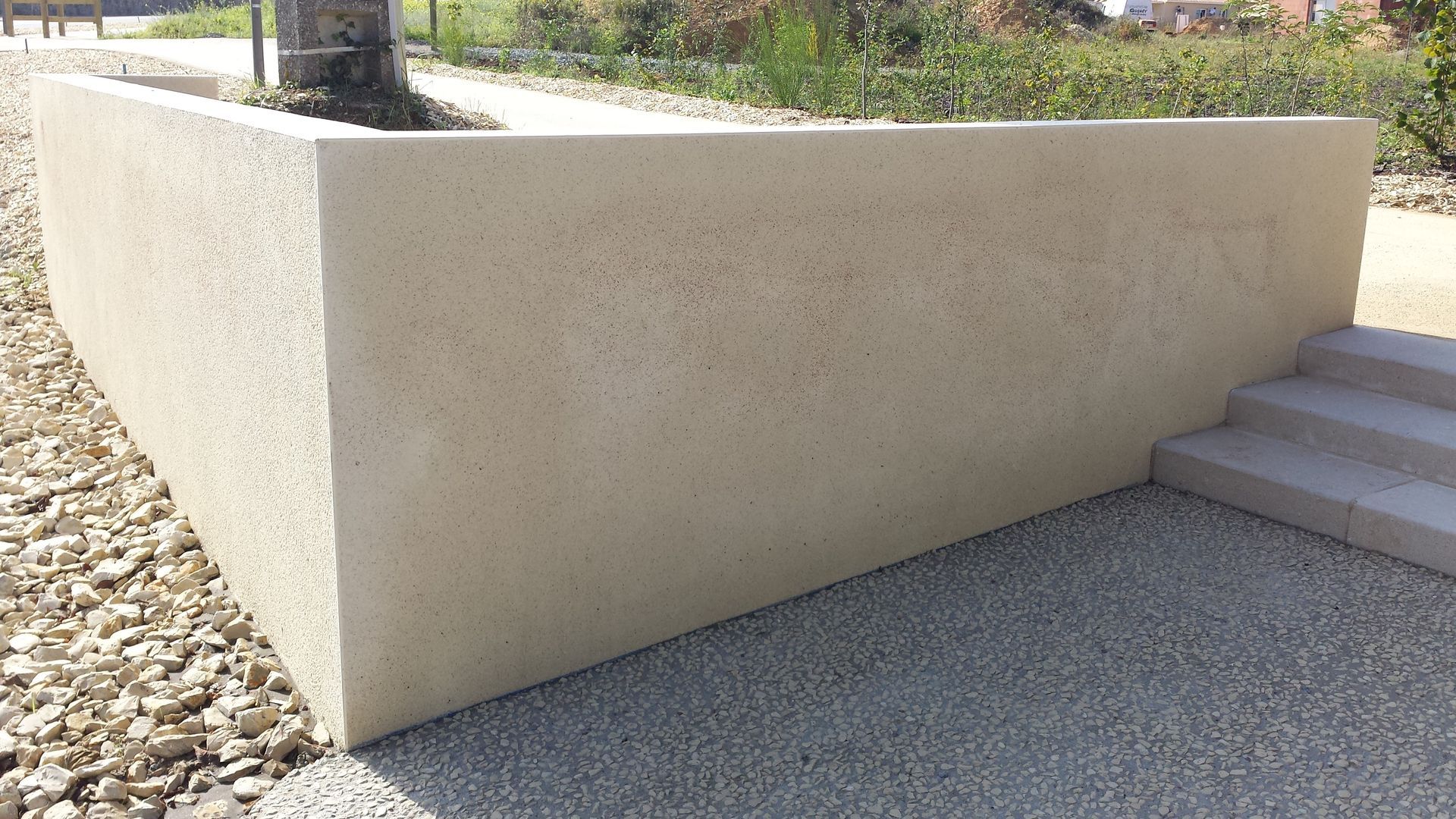 Muret en béton beige à côté d'un chemin de gravier et de marches à l'extérieur