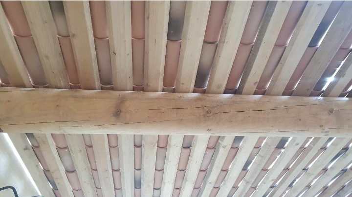 Vue de dessous d'un plafond à lattes de bois, la lumière filtrant à travers les interstices.