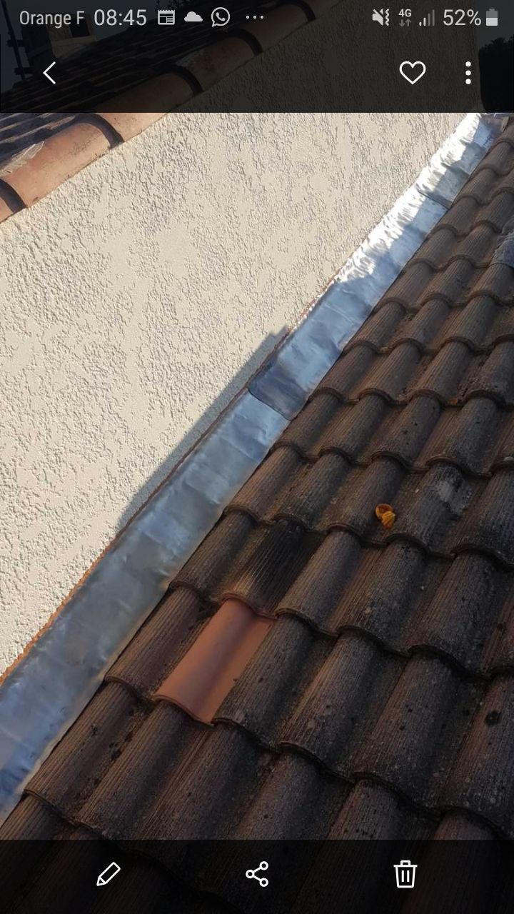 Vue inclinée d'un toit de tuiles à côté d'un mur blanc, vue depuis un écran de smartphone.