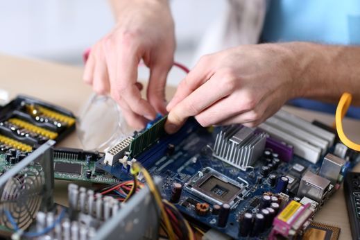 Eine Person arbeitet mit einem Schraubenzieher an der Hauptplatine eines Computers.