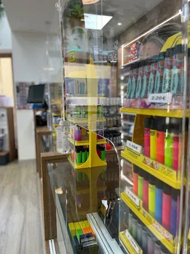 Dentro de una tienda, estantes amarillos exhiben encendedores detrás de una barrera transparente.