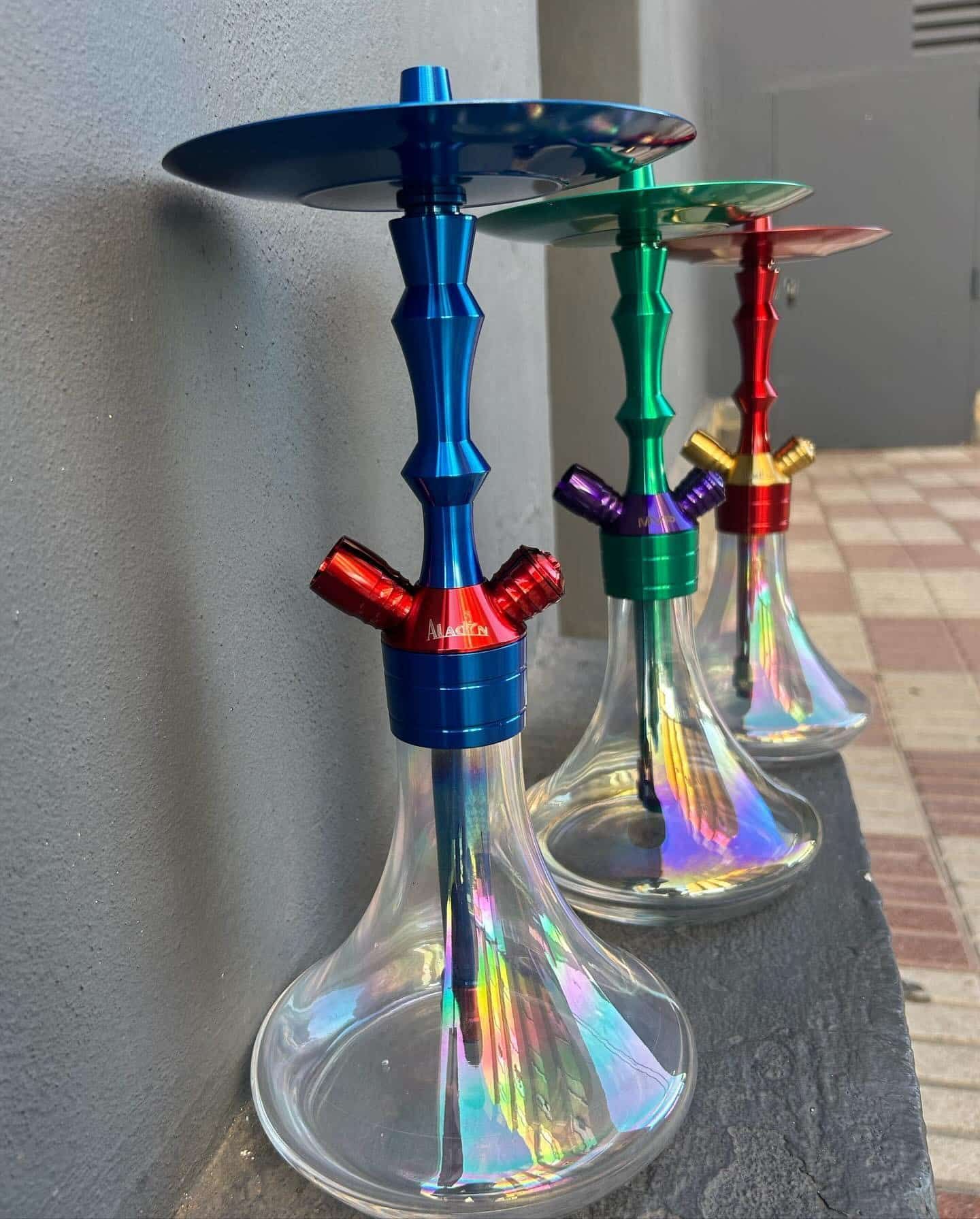 Cuatro coloridas pipas de agua alineadas al aire libre, cada una con un tallo y una base de diferente color.