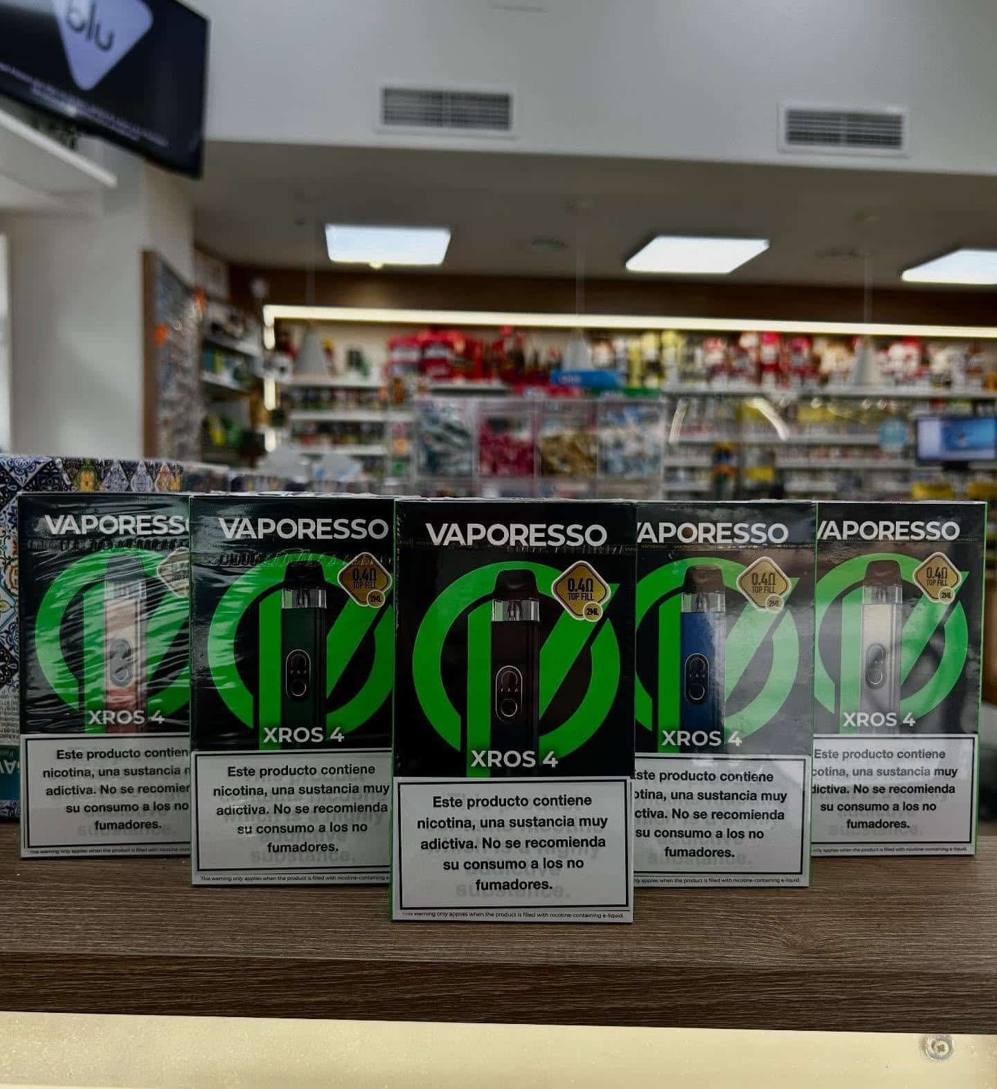 Cajas de vapeo Vaporesso XROS 4 exhibidas en el estante de una tienda, con empaque verde y negro.