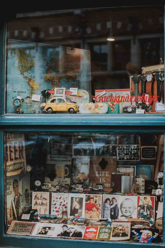 Un escaparate muestra artículos vintage: coches de juguete, mapas, postales, cámaras y correas de reloj.