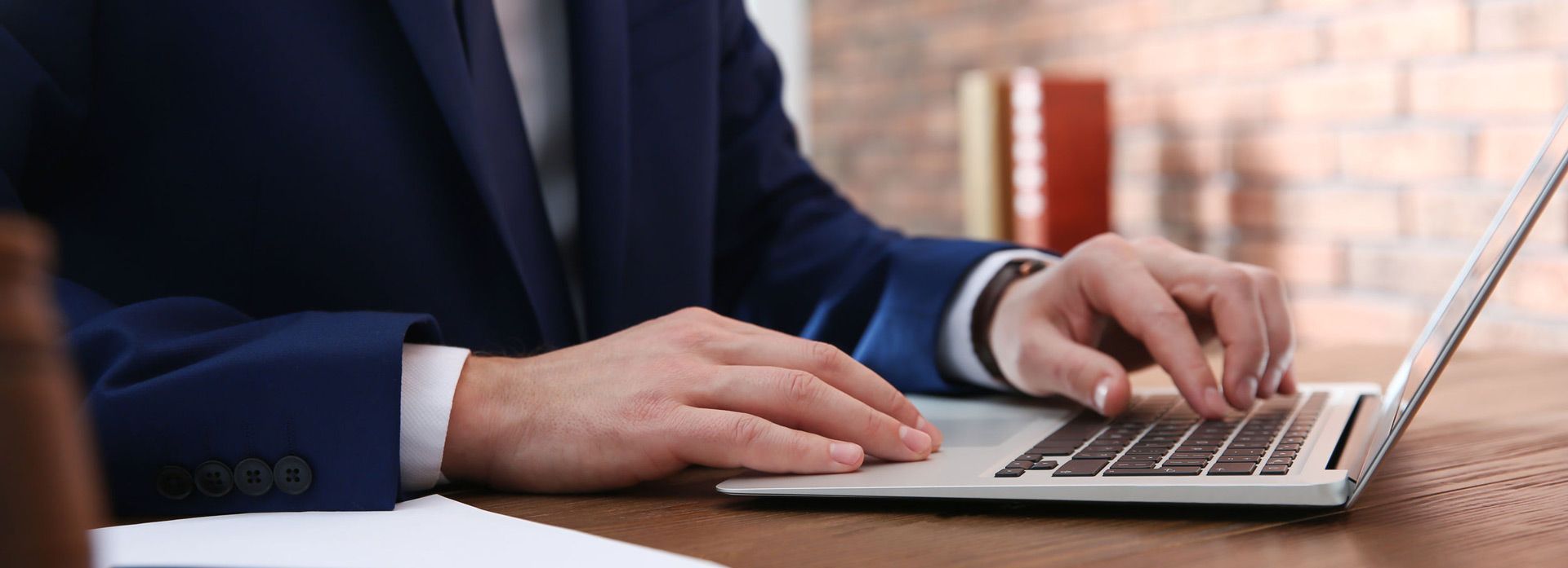 Un hombre con traje está escribiendo en una computadora portátil.