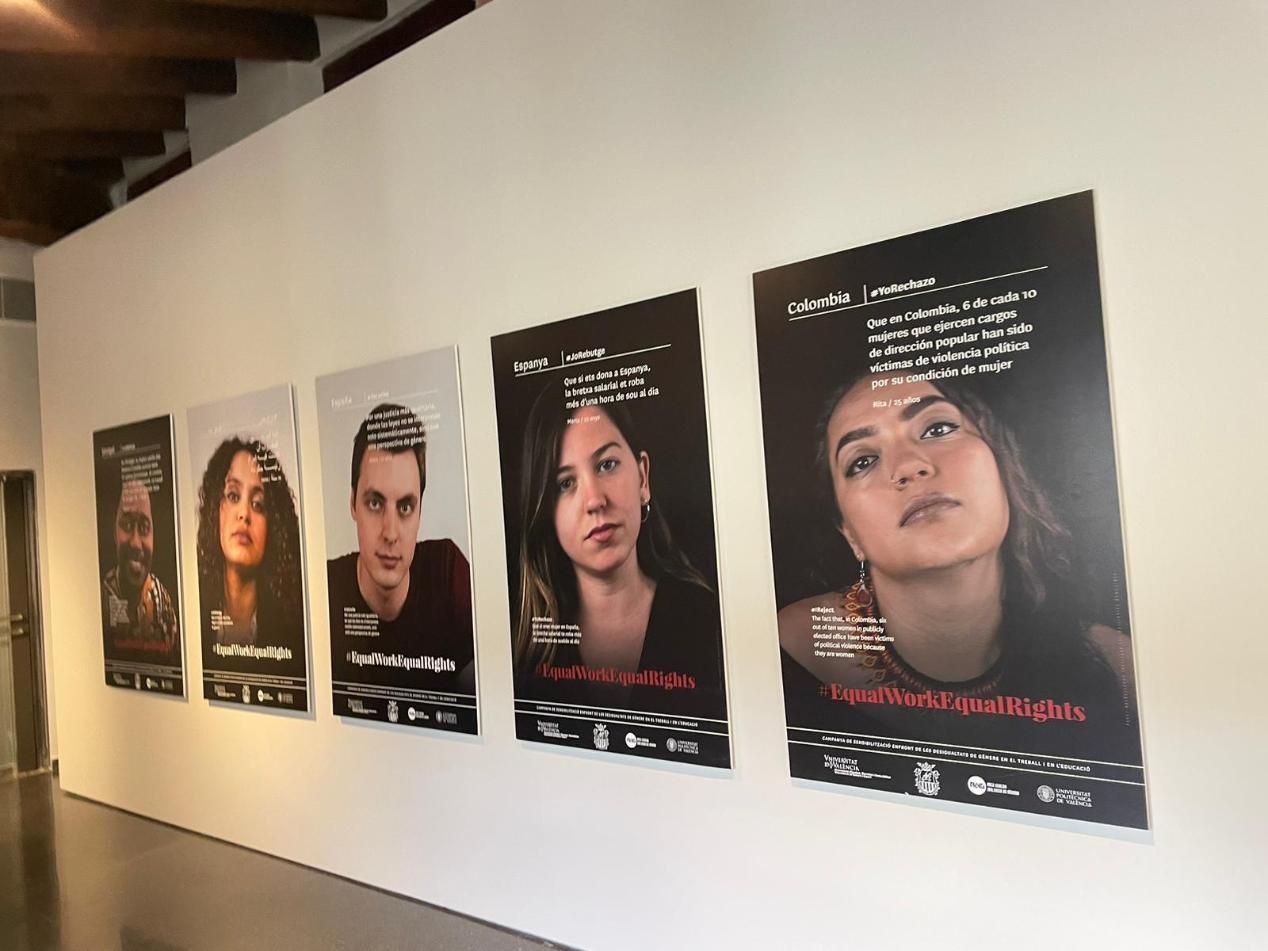 Pósteres sobre una pared blanca. Cada uno presenta el retrato de una persona, texto y logotipos.