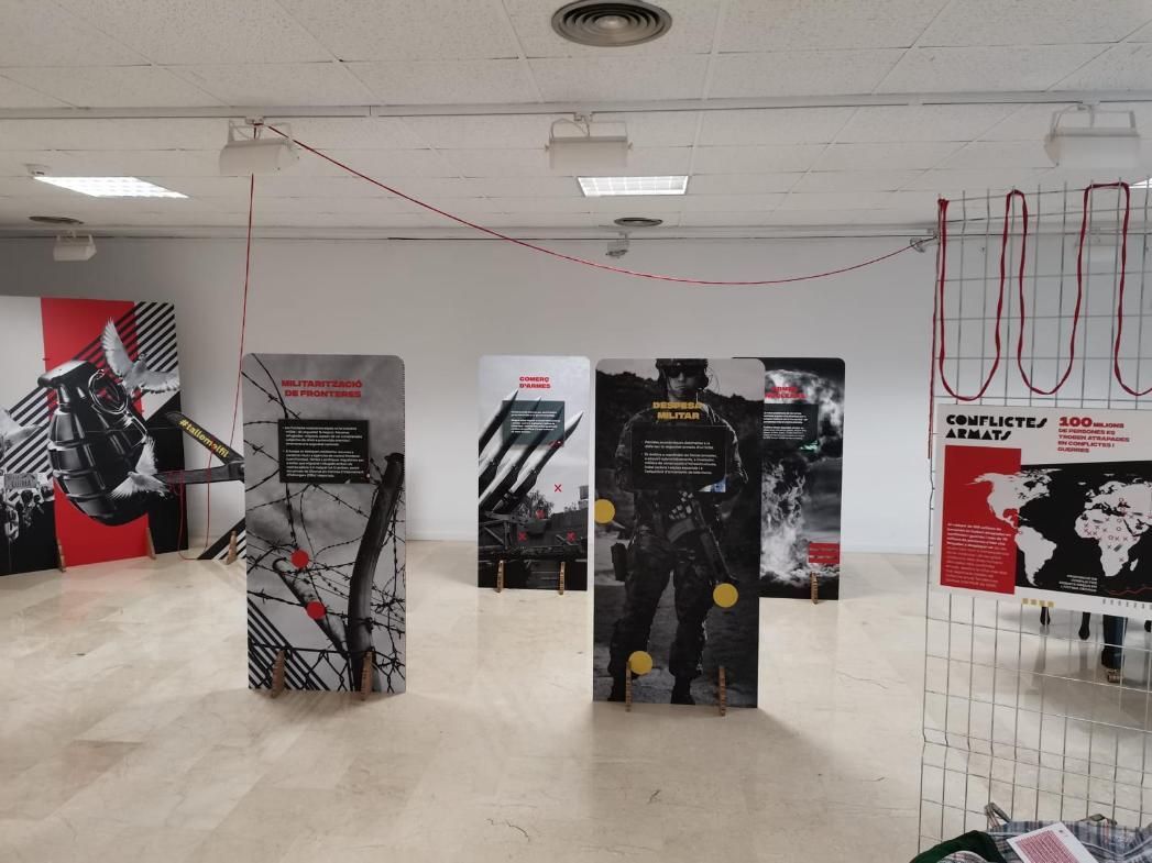 Galería con carteles y un cordón de rayas rojas. Gráficos negros y rojos, figuras de soldados.