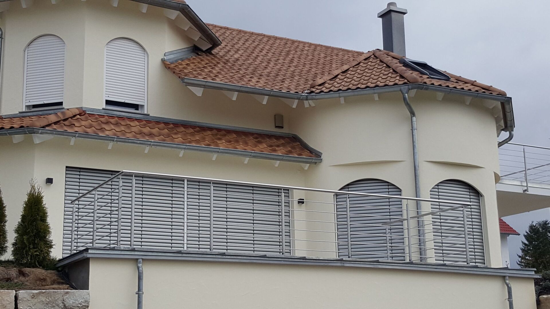 Weißes Haus mit außen Rolladen am Balkon