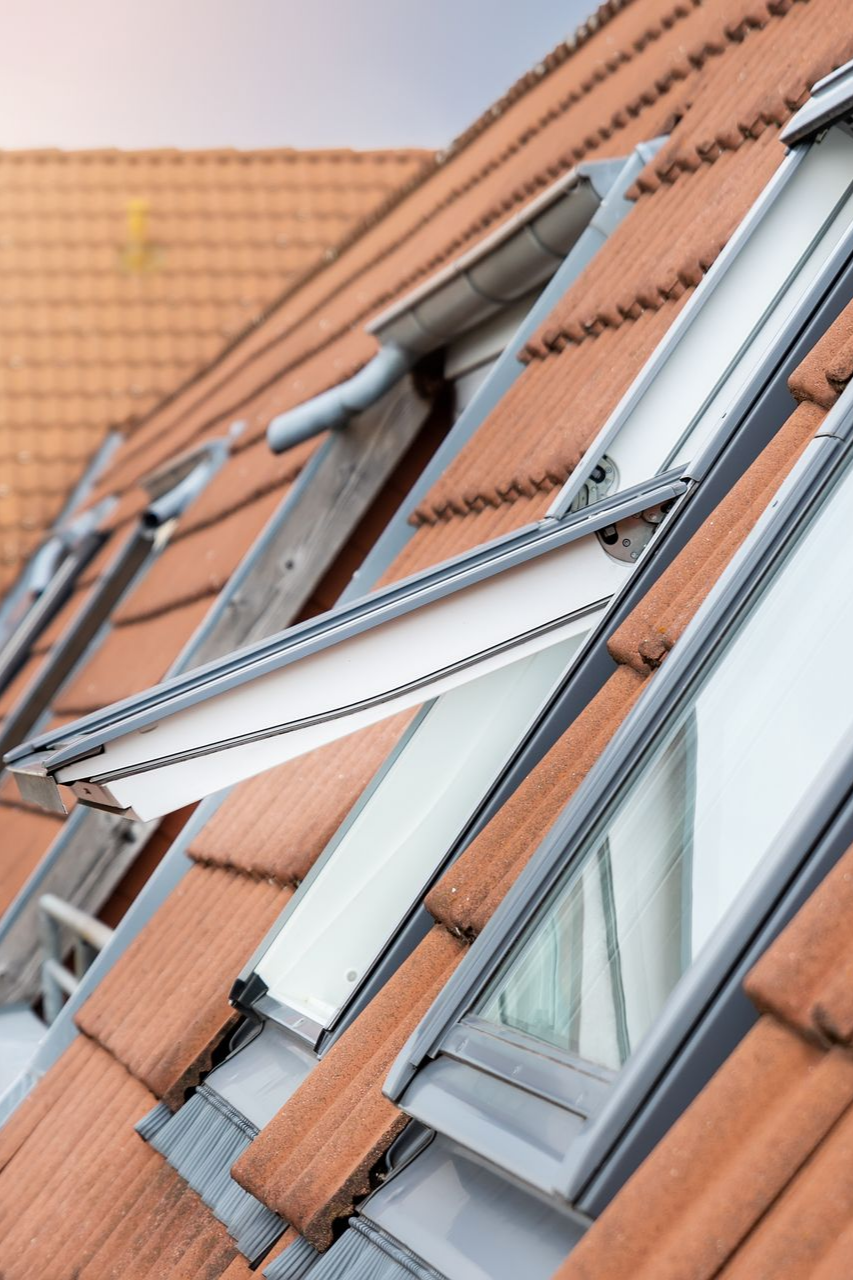 Vue en angle du toit avec puits de lumière ouverts et tuiles orange.