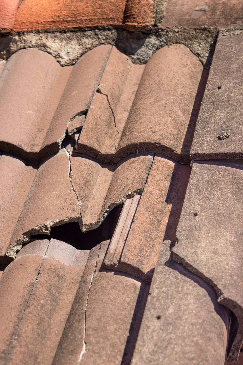 Tuiles de toit en terre cuite endommagées et fissurées.