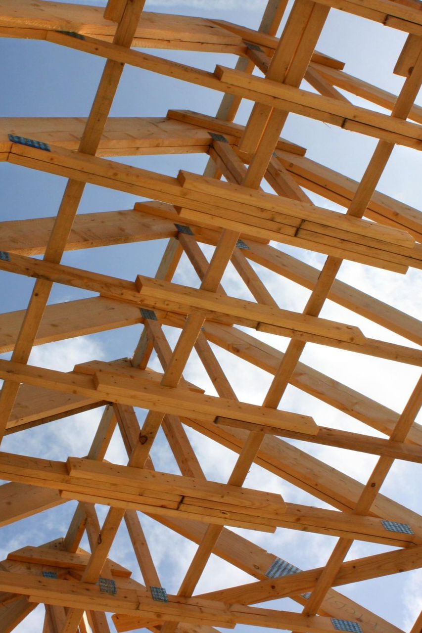 Charpente de toit en bois se détachant sur un ciel bleu.