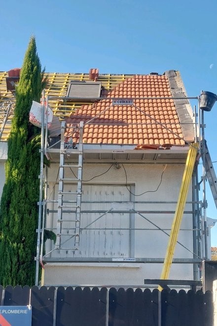 Toiture en réparation, échafaudages, tuiles orange.