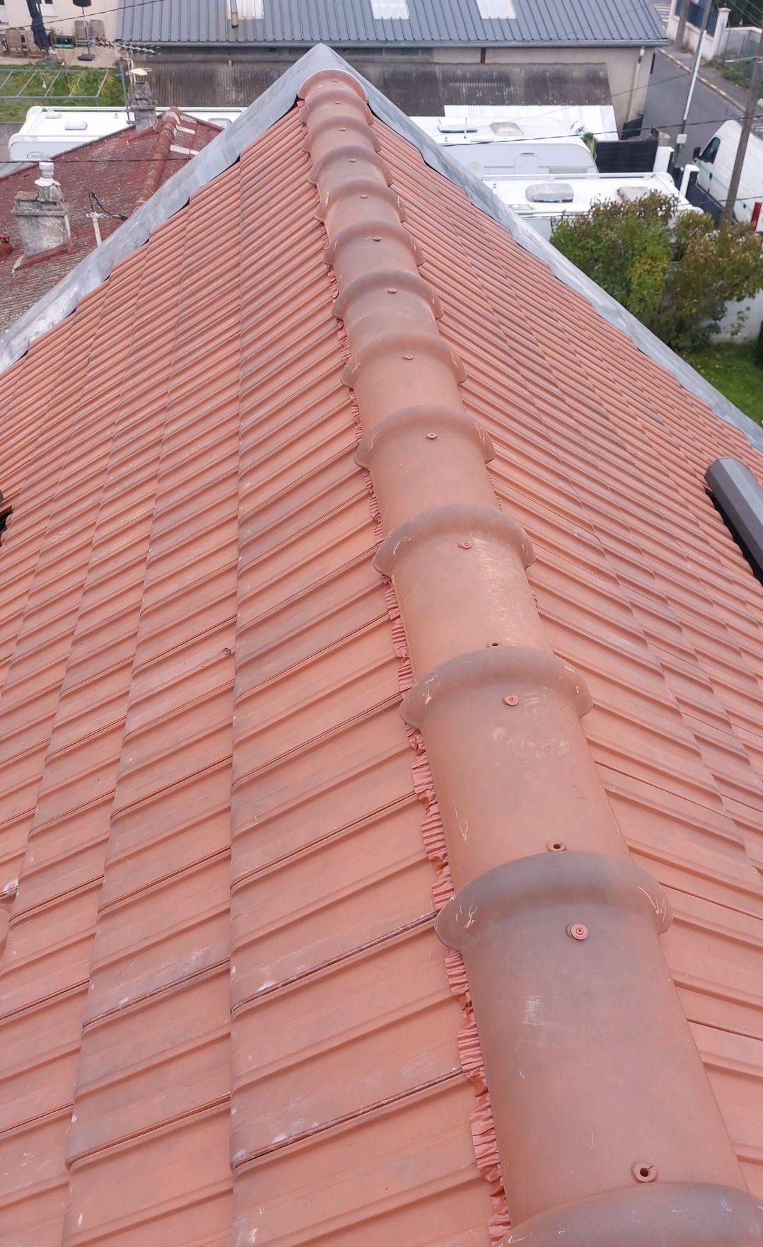 Toit de tuile rouge avec une arête centrale, vue du dessus.