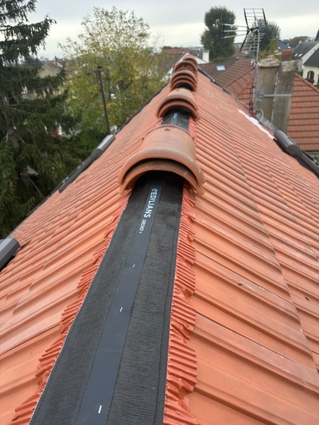 Toiture en tuile rouge avec une bande noire centrale.