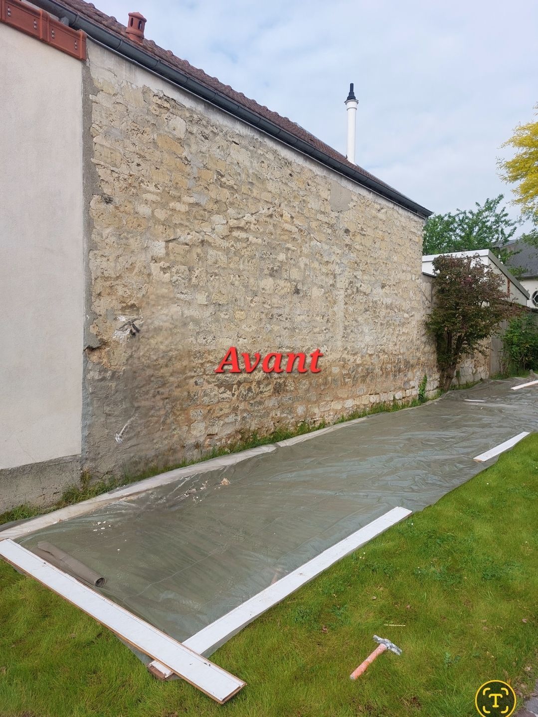 Mur extérieur avant rénovation. Bâtiment en pierre avec nouvelle allée en béton, inscription rouge Avant.