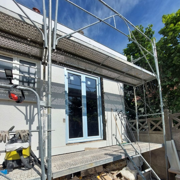 Façade de la maison en construction, échafaudages autour de la porte d'entrée.