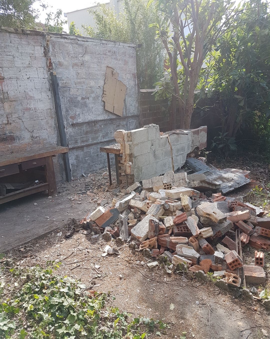 Tas de briques et de débris provenant d'un mur démoli, dans un jardin.