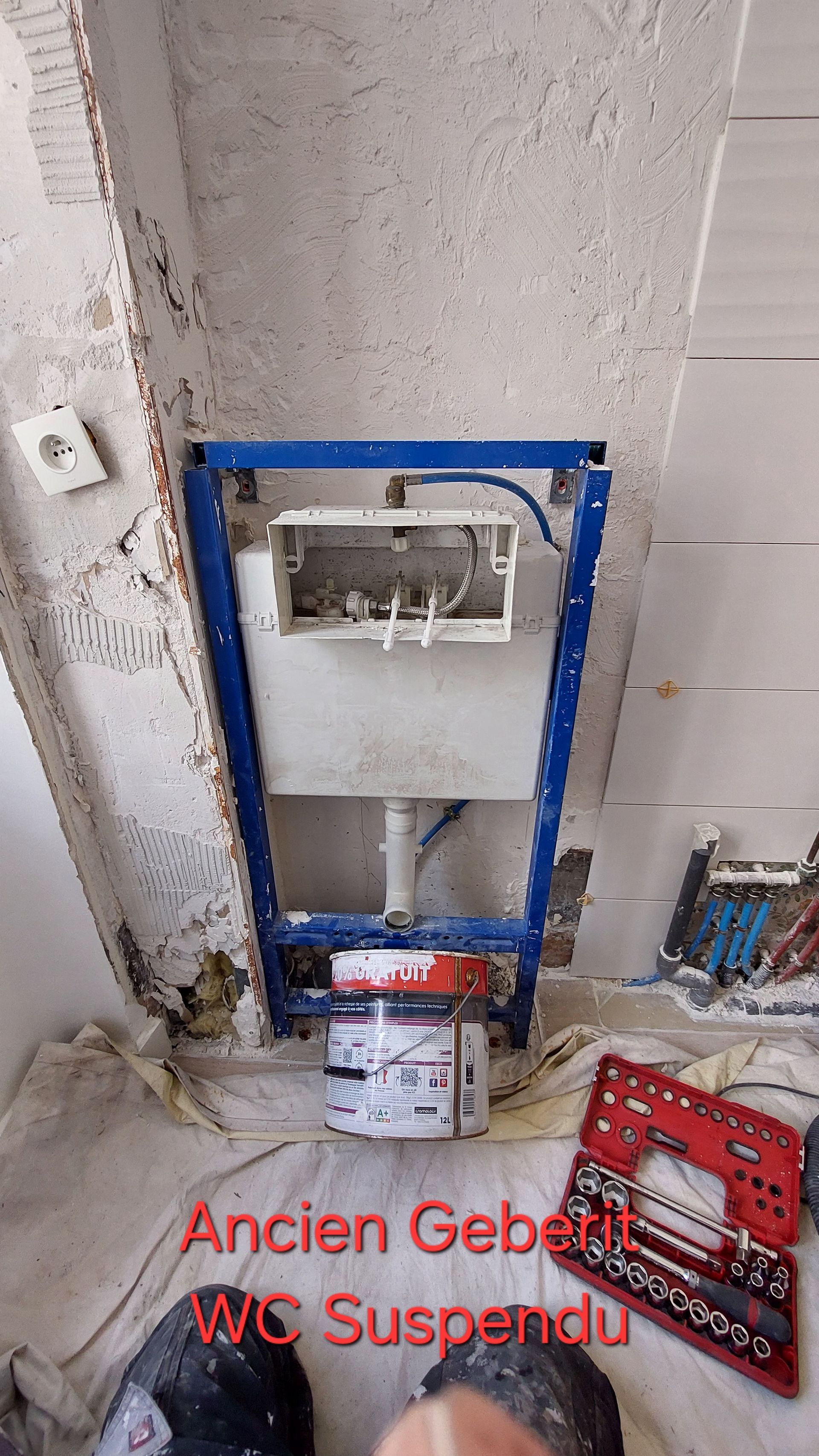 Cadre métallique bleu avec réservoir de toilettes blanc fixé au mur ; les outils sont rangés en dessous.