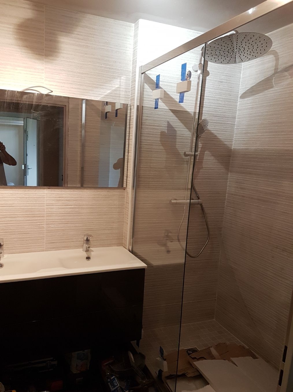 Salle de bains moderne avec cabine de douche en verre, murs blancs et meuble-lavabo foncé.