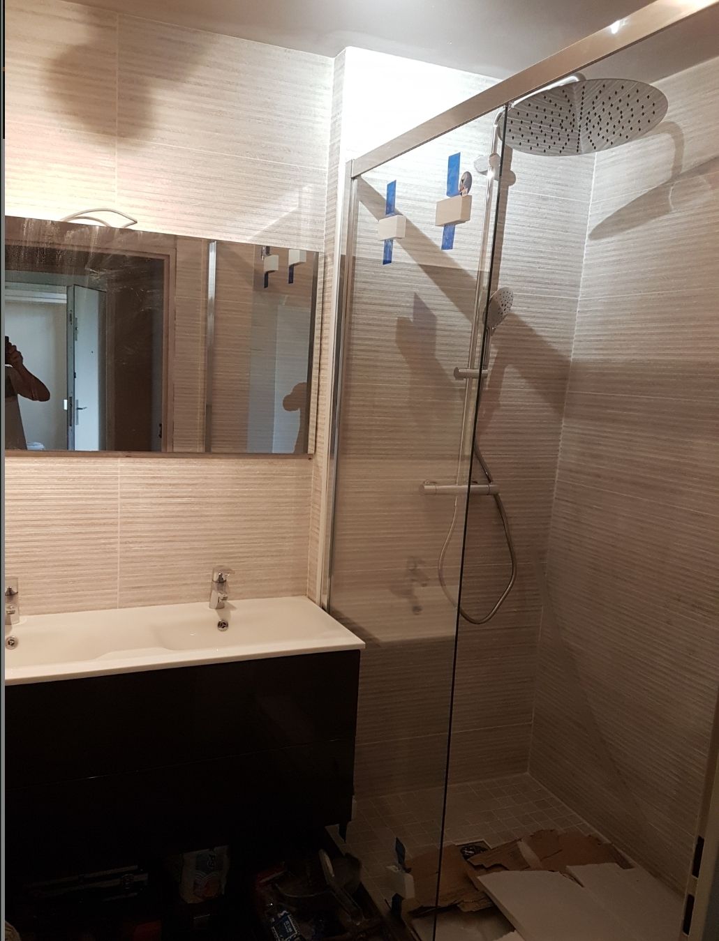 Salle de bains avec douche en verre, lavabo et miroir.