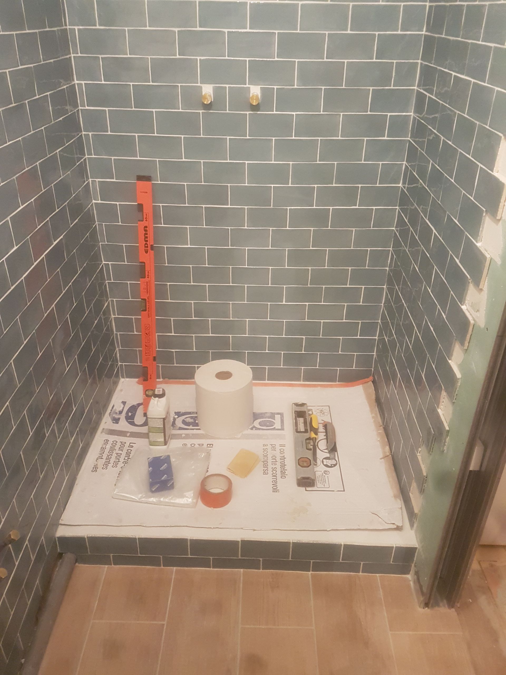 Cabine de douche carrelée de carreaux bleus, outils et matériaux de construction.