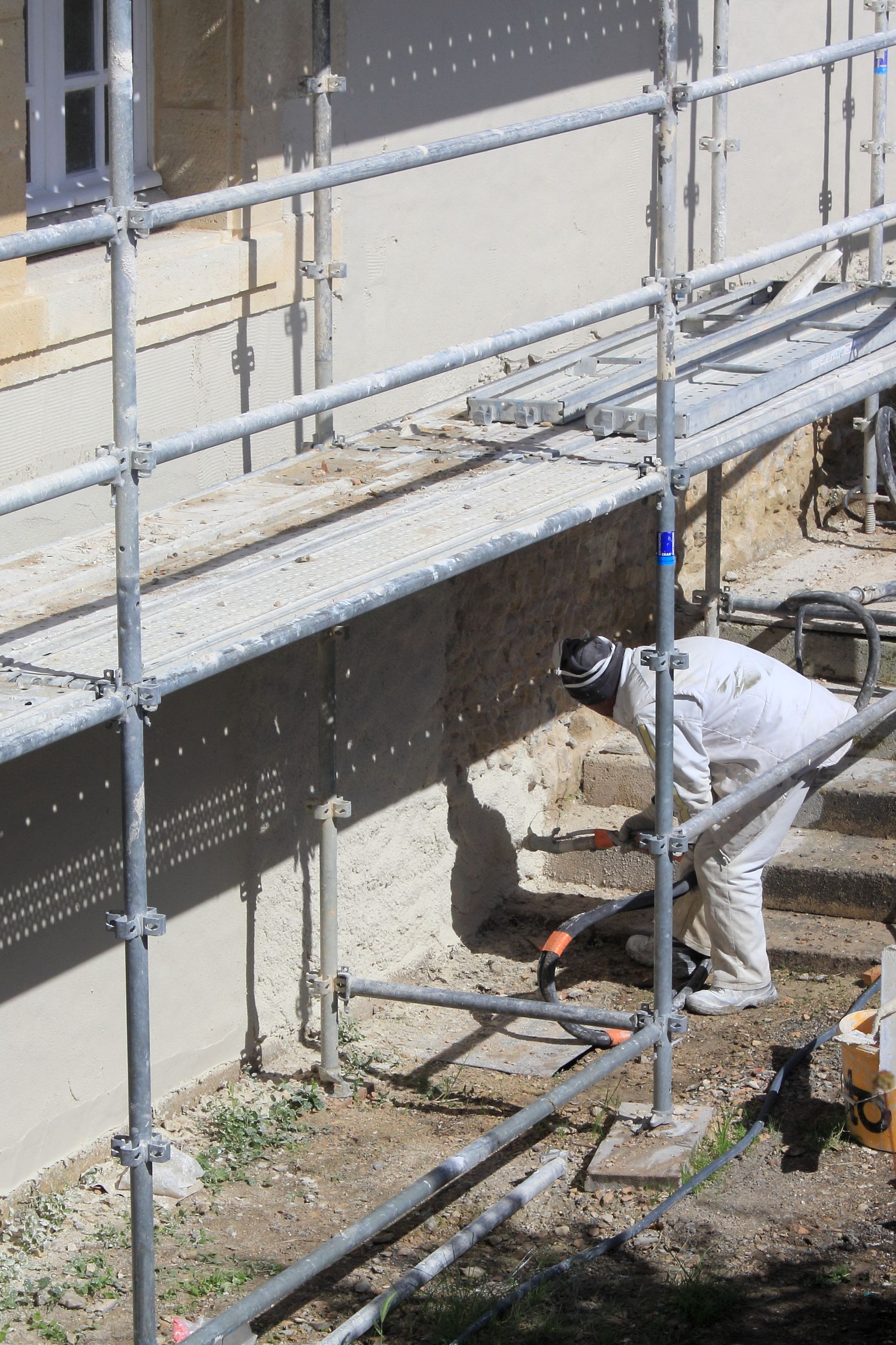 Projection d'enduit sur le bas d'une façade.