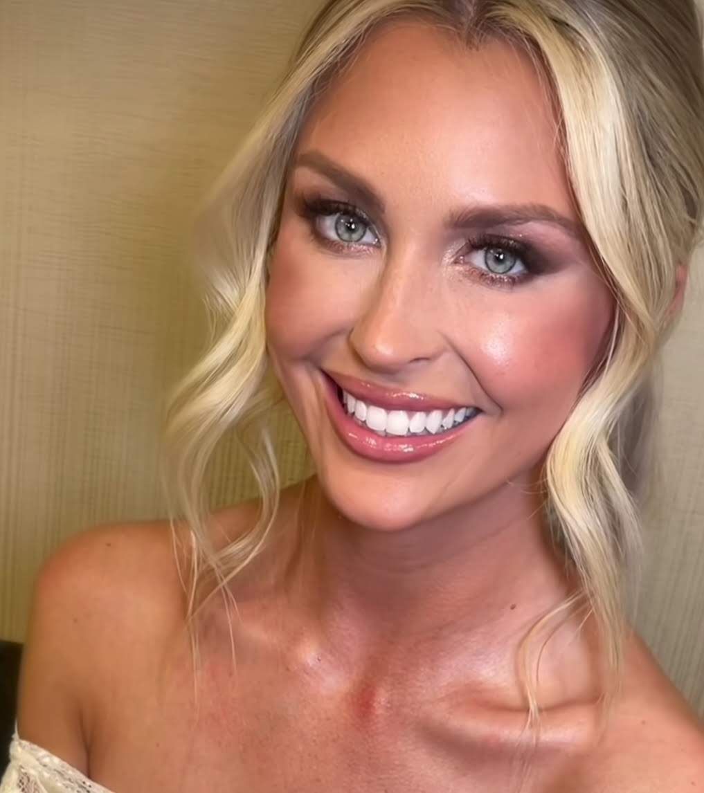 Mujer con recogido rubio sonríe, maquillada, piel iluminada.